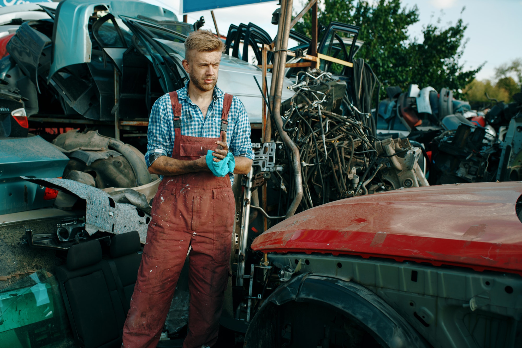 Male repairman with towel on car junkyard